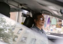 Skupiony azjatycki kierowca w okularach prowadzi auto w mieście