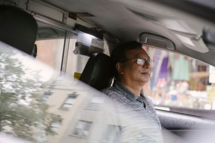 Skupiony azjatycki kierowca w okularach prowadzi auto w mieście