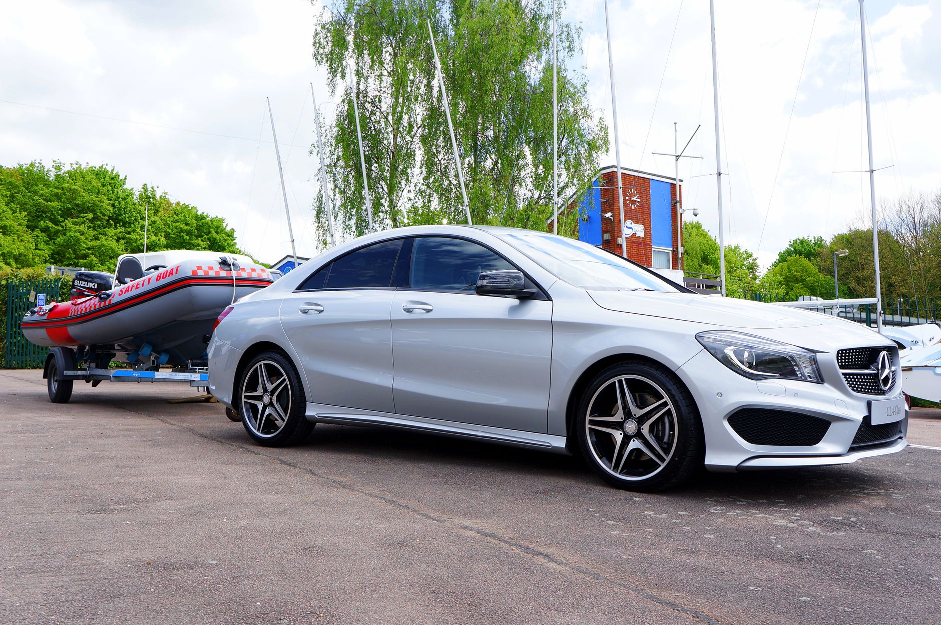 Srebrne auto osobowe ciągnie przyczepę z łodzią przy marinie