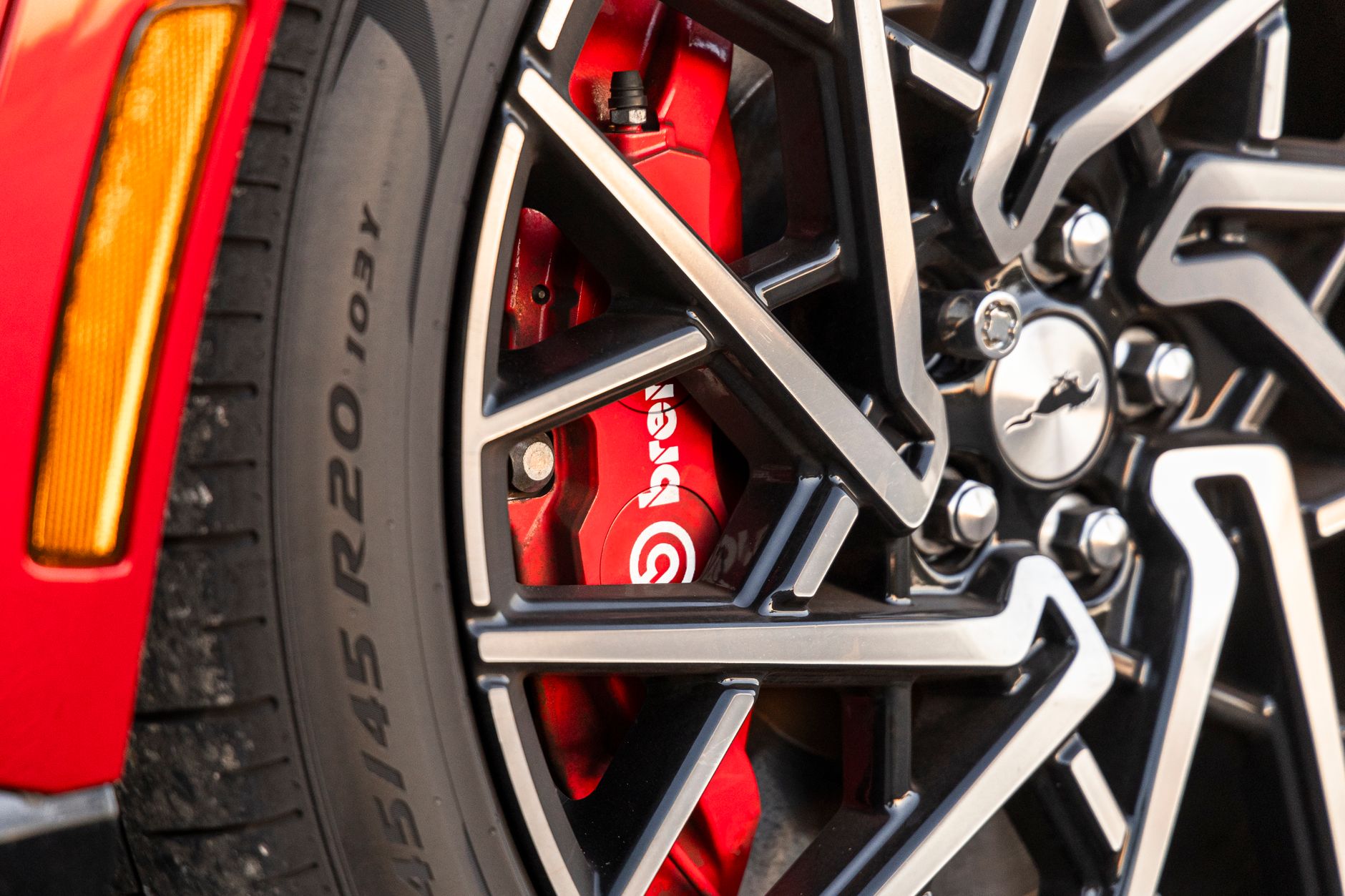 Zbliżenie czerwonego zacisku hamulcowego Brembo i aluminiowej felgi samochodu