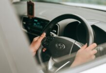 Dłonie kierowcy trzymające kierownicę w prawidłowej pozycji w czasie jazdy
