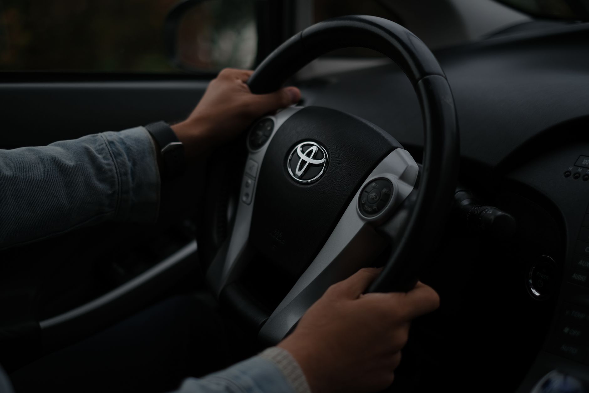 Dłonie na kierownicy Toyoty we wnętrzu ciemnego samochodu