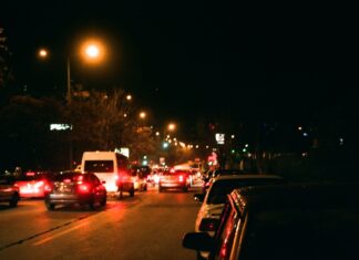 Ćwiczenia z panowania nad autem w korku i podczas częstego ruszania Nocna miejska ulica pełna samochodów i jasnych świateł